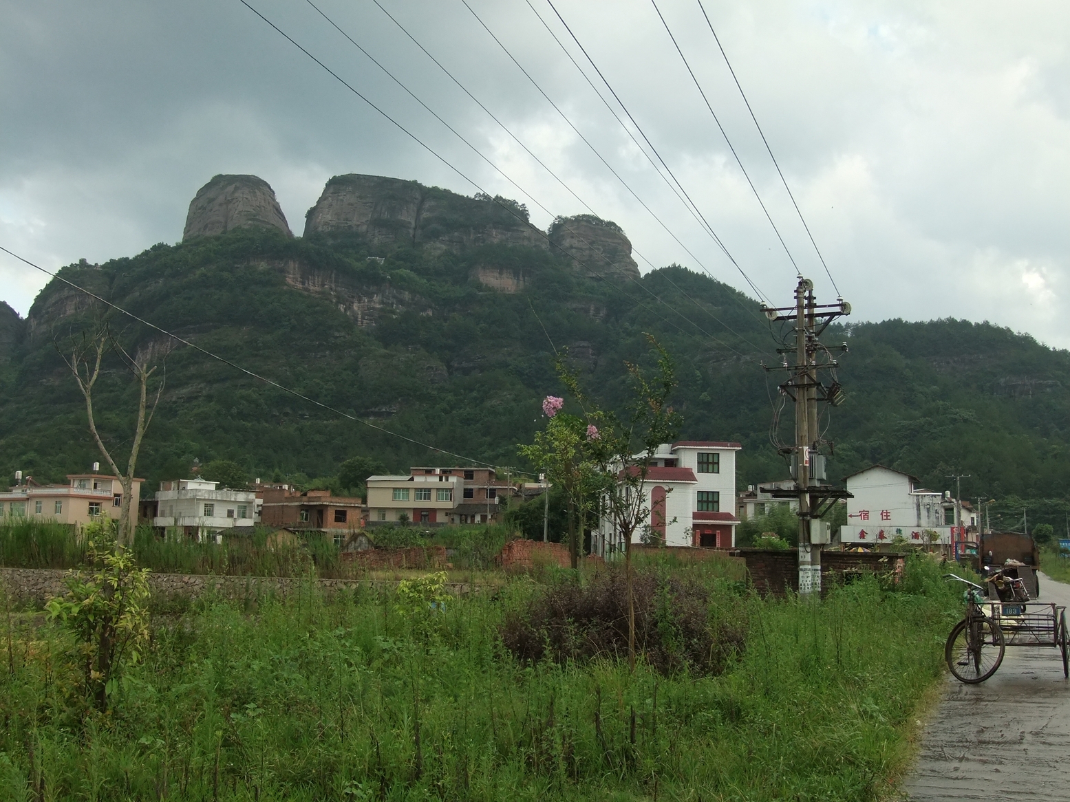 Distant view of Guanzhai Mountain in Liancheng, Fujian — red sandstone cliffs rising sharply above subtropical forest