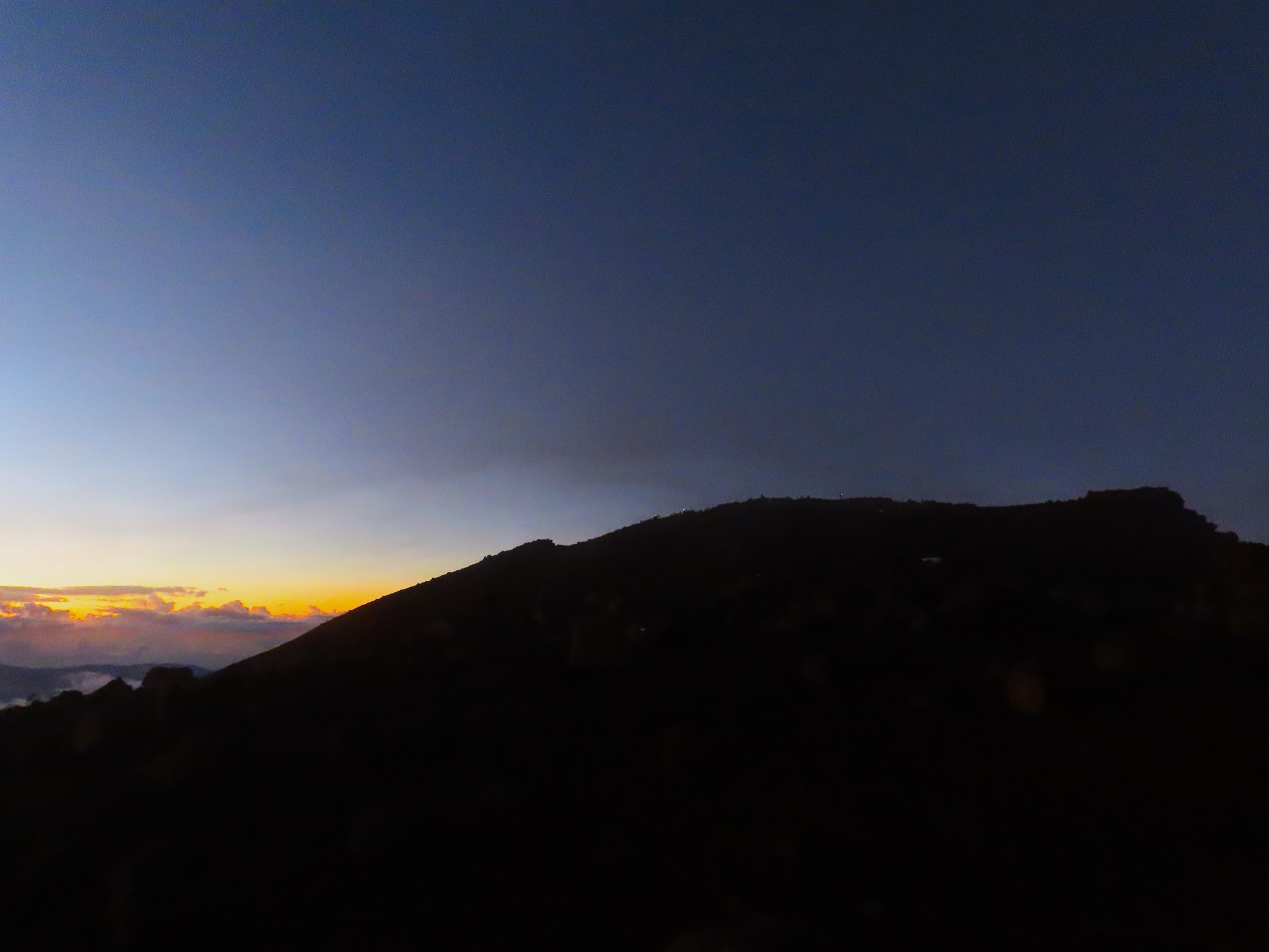 Sunrise from the summit of the Piton des Neiges, with volcanic bombs in the foreground and clouds filling the cirques below