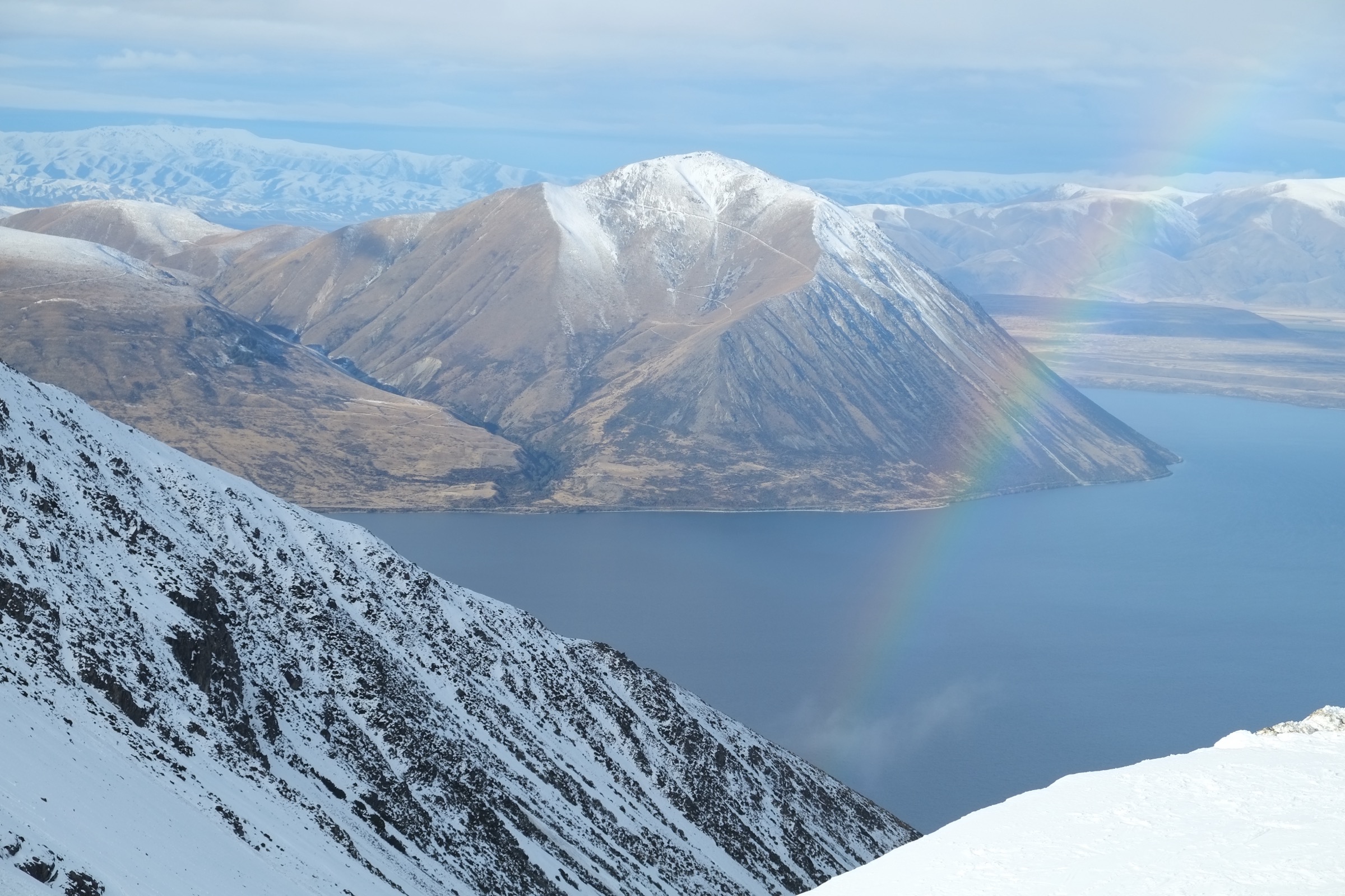 View from the top of the Ōhau Snow Fields across Lake Ōhau with a rainbow