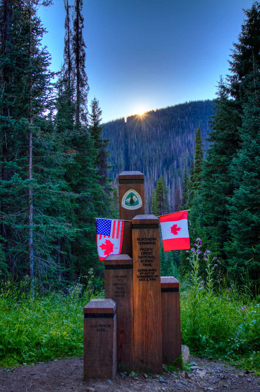 The PCT northern terminus monument at the US–Canada border at sunset