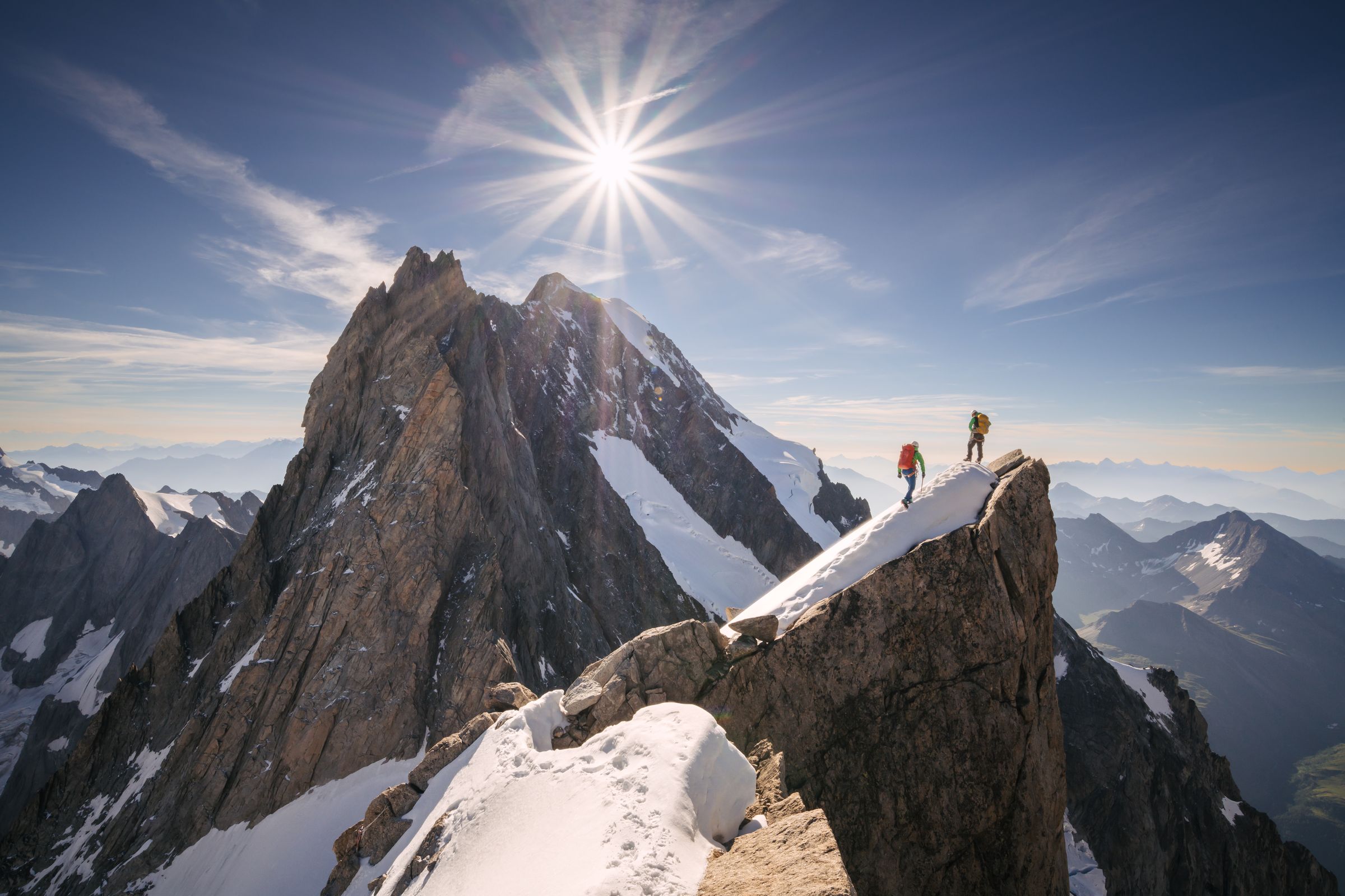 Deux alpinistes progressant sur une arête granitique corniche dans les Alpes