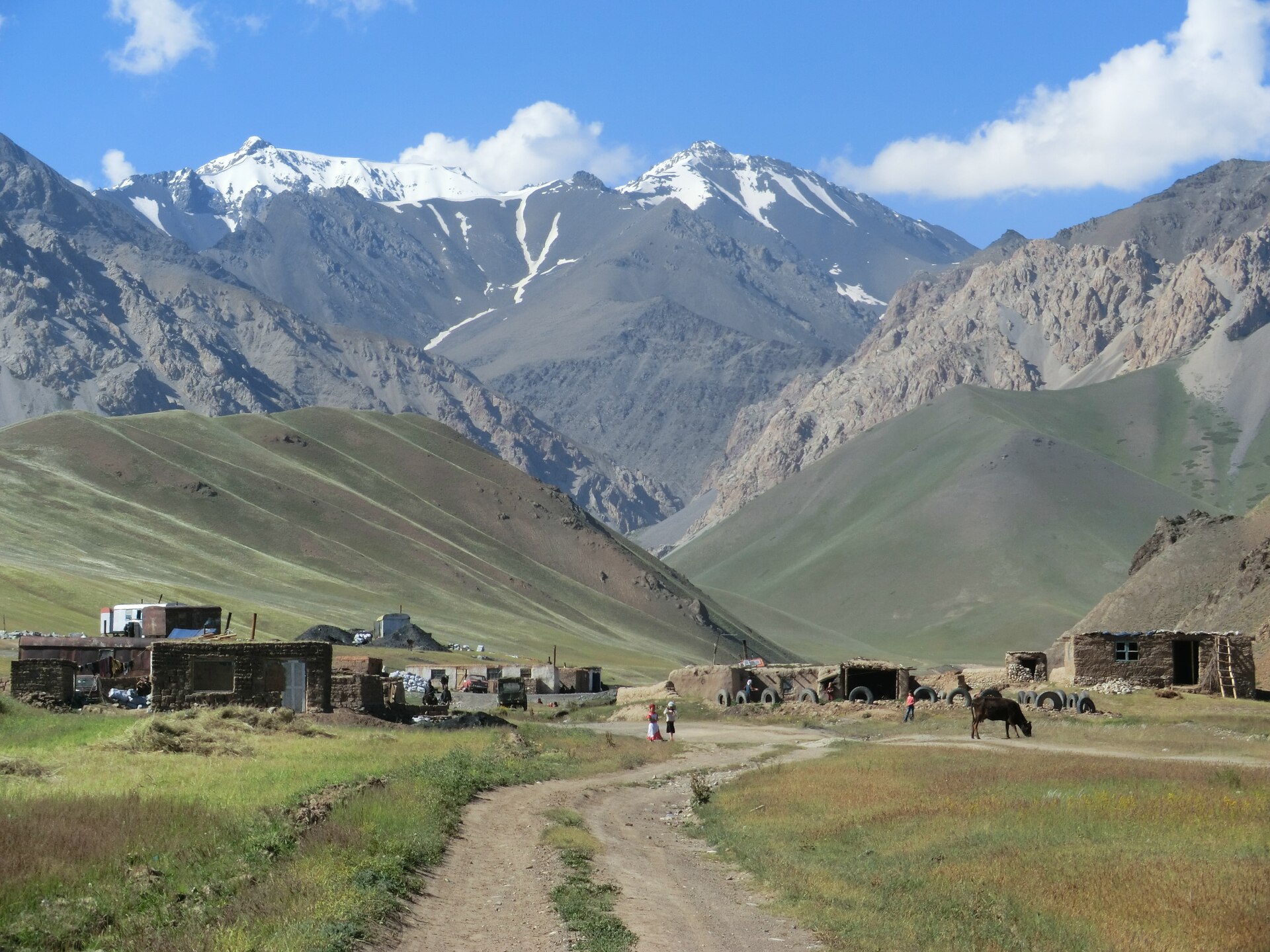 A small Alay settlement beneath steep grey and snow-covered peaks