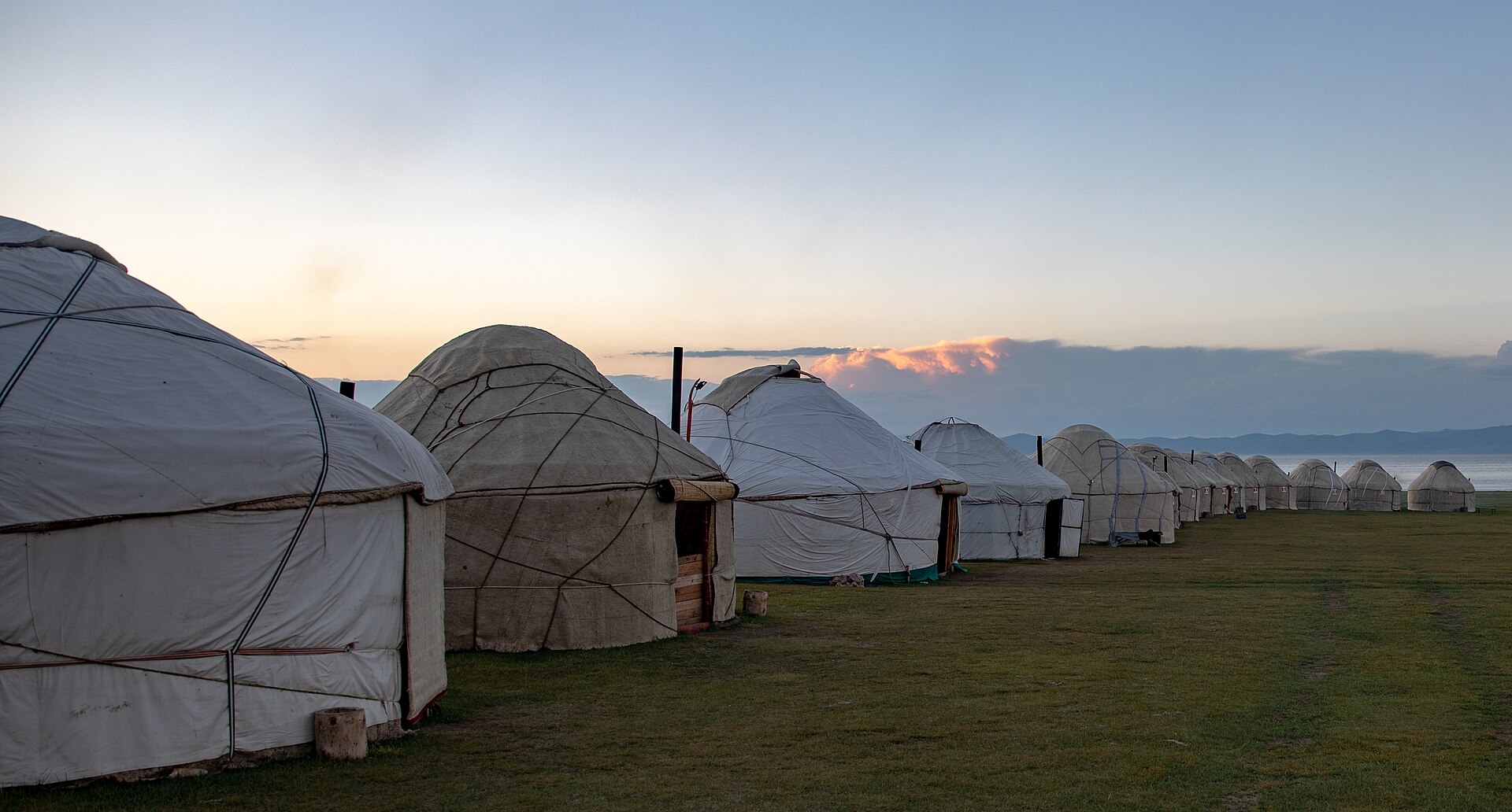 An evening yurt camp spread across green pasture at Song-Kul