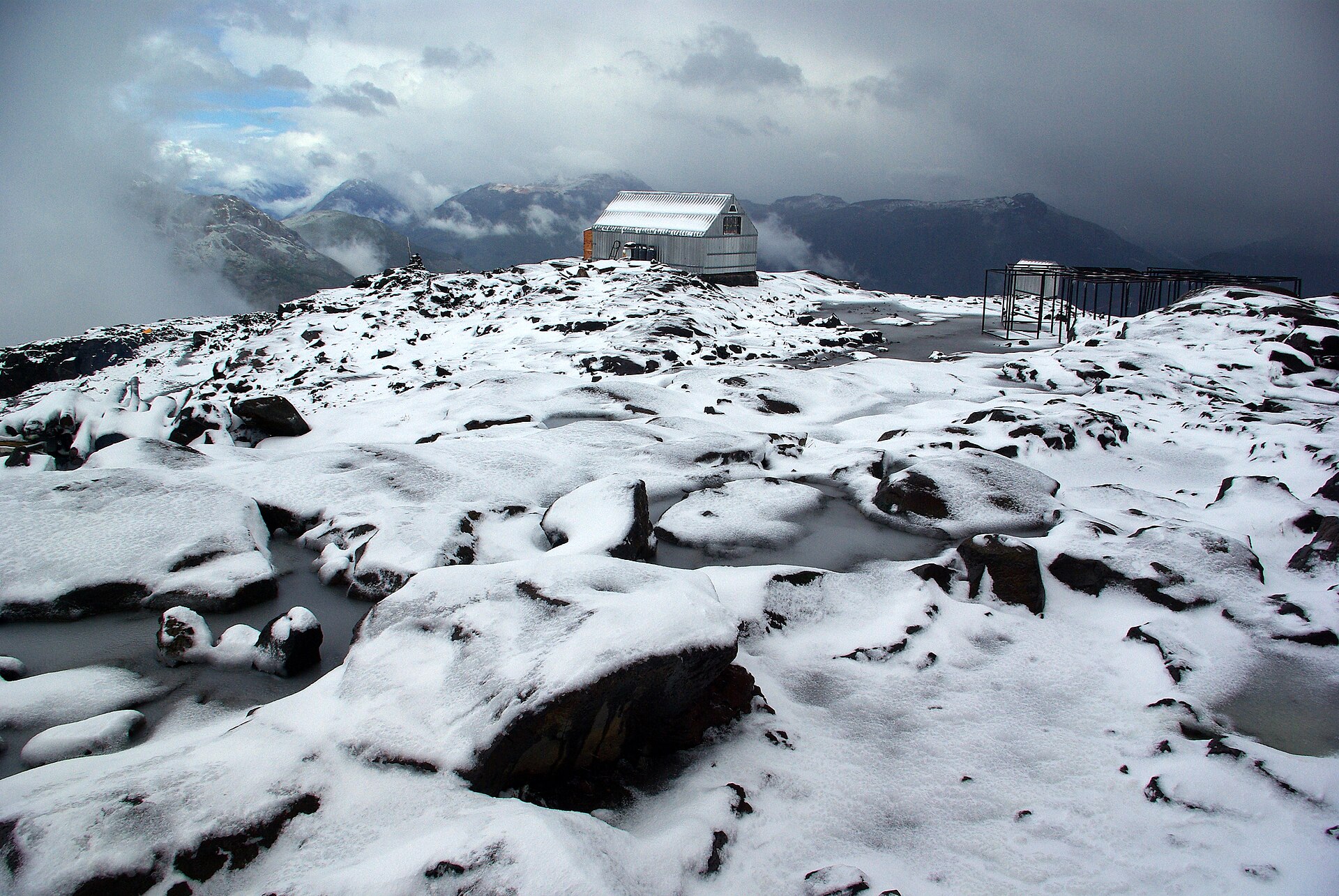 Refugio Otto Meiling on a snowy ridge beneath cloud on Cerro Tronador