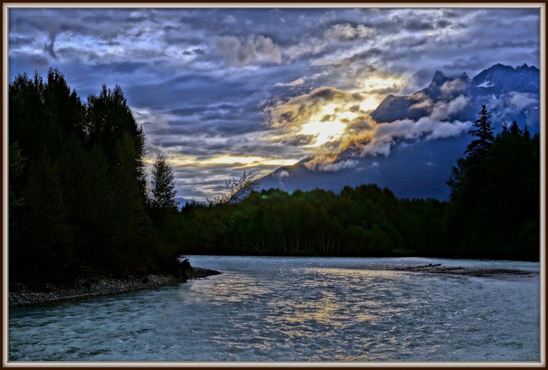 The Bella Coola River flowing beneath cloud-wrapped mountains
