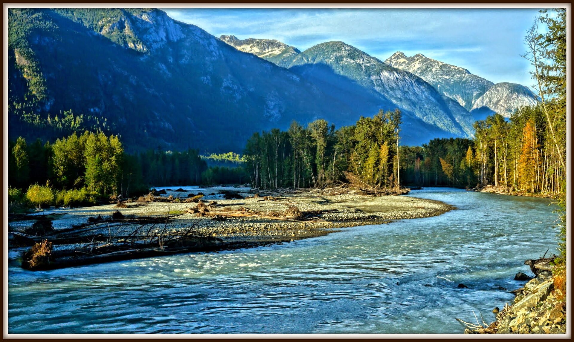 A broad river braid crossing the Bella Coola Valley below forested mountains