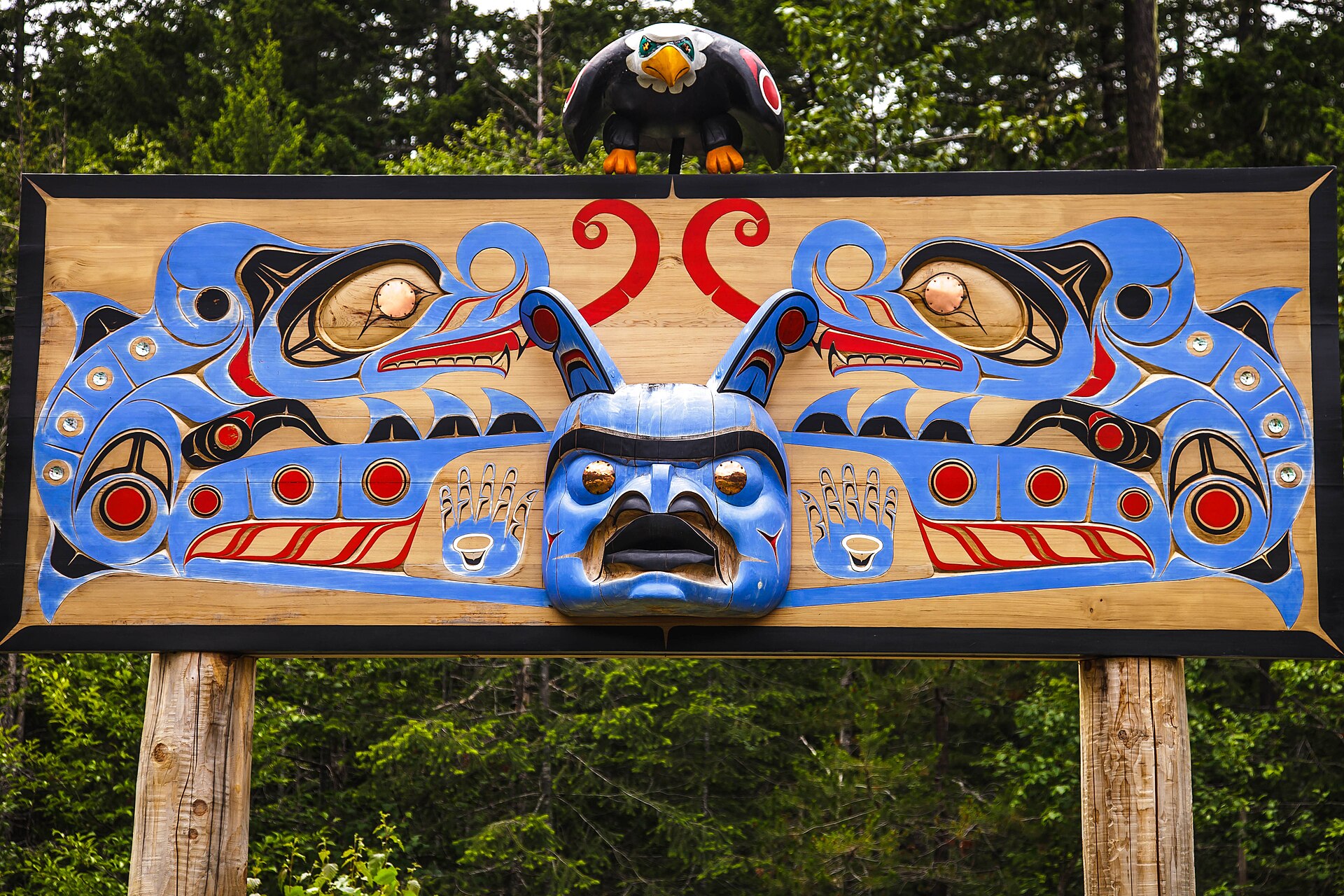 A carved and painted Nuxalk memorial panel topped by an eagle figure in the Bella Coola Valley