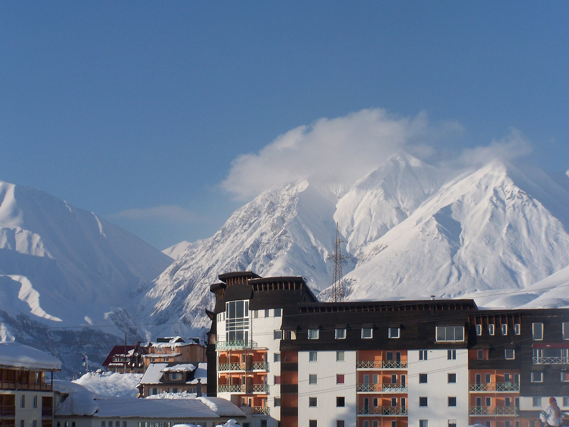 A snowy Gudauri hotel beneath a steep cloud-wrapped Caucasus peak