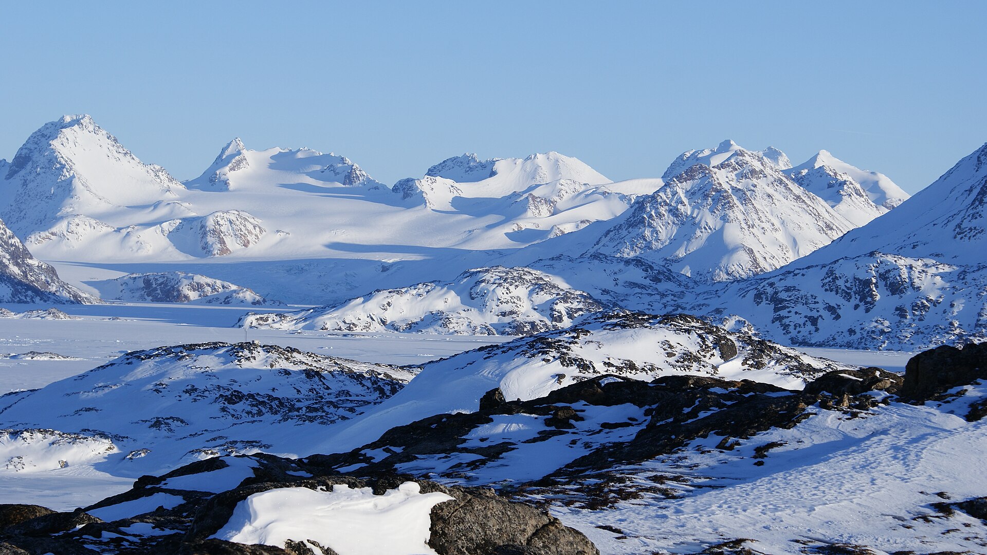 The broken front of Apusiaajik Glacier beyond floating sea ice near Kulusuk