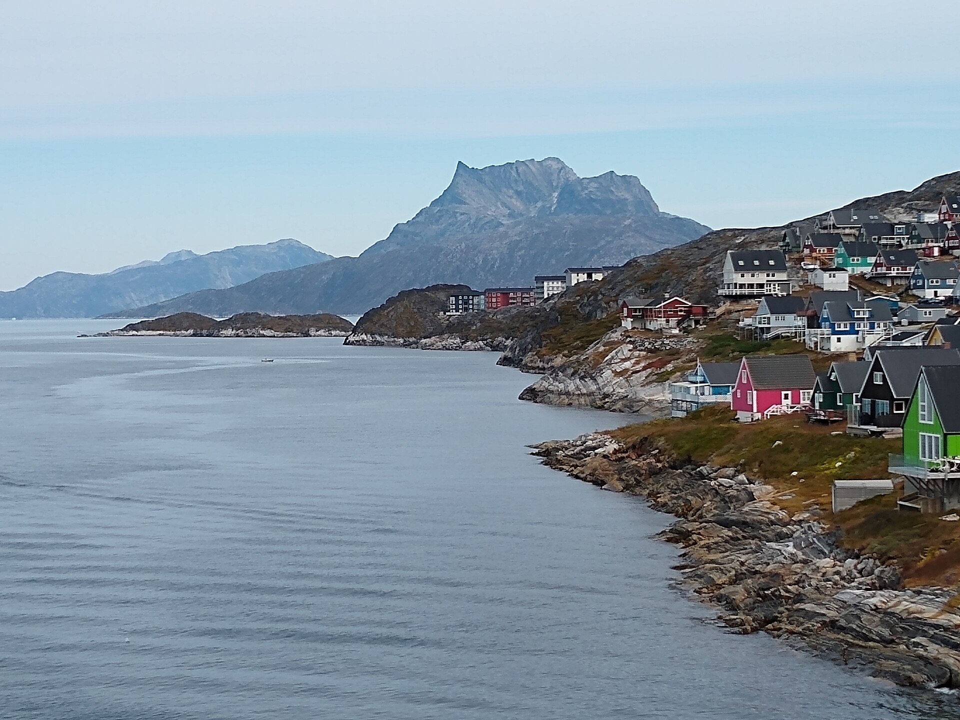 A rugged mountain peak rising behind colourful waterfront houses in Nuuk
