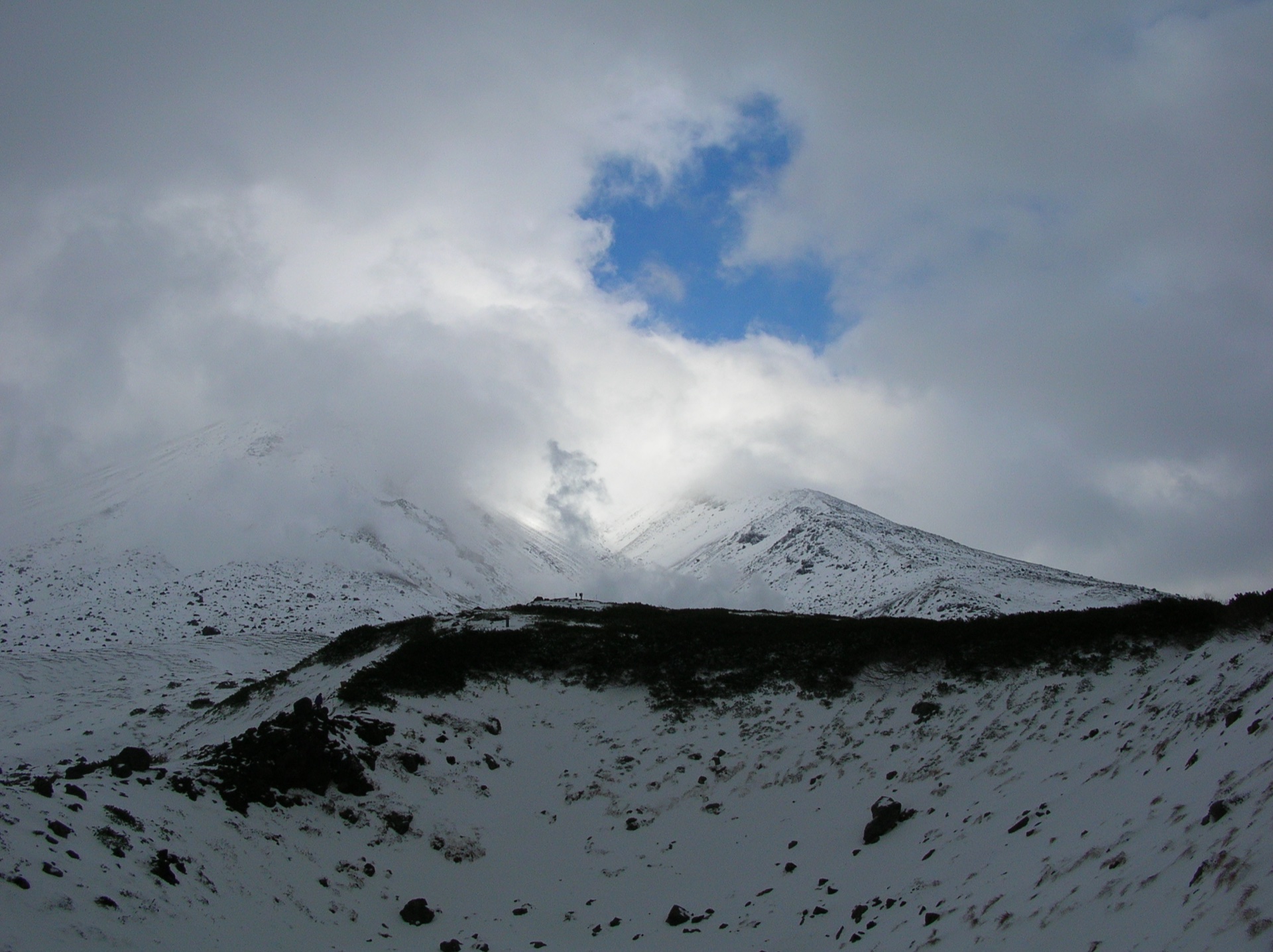 Cloud breaking around the snow-covered upper cone of Mount Asahidake