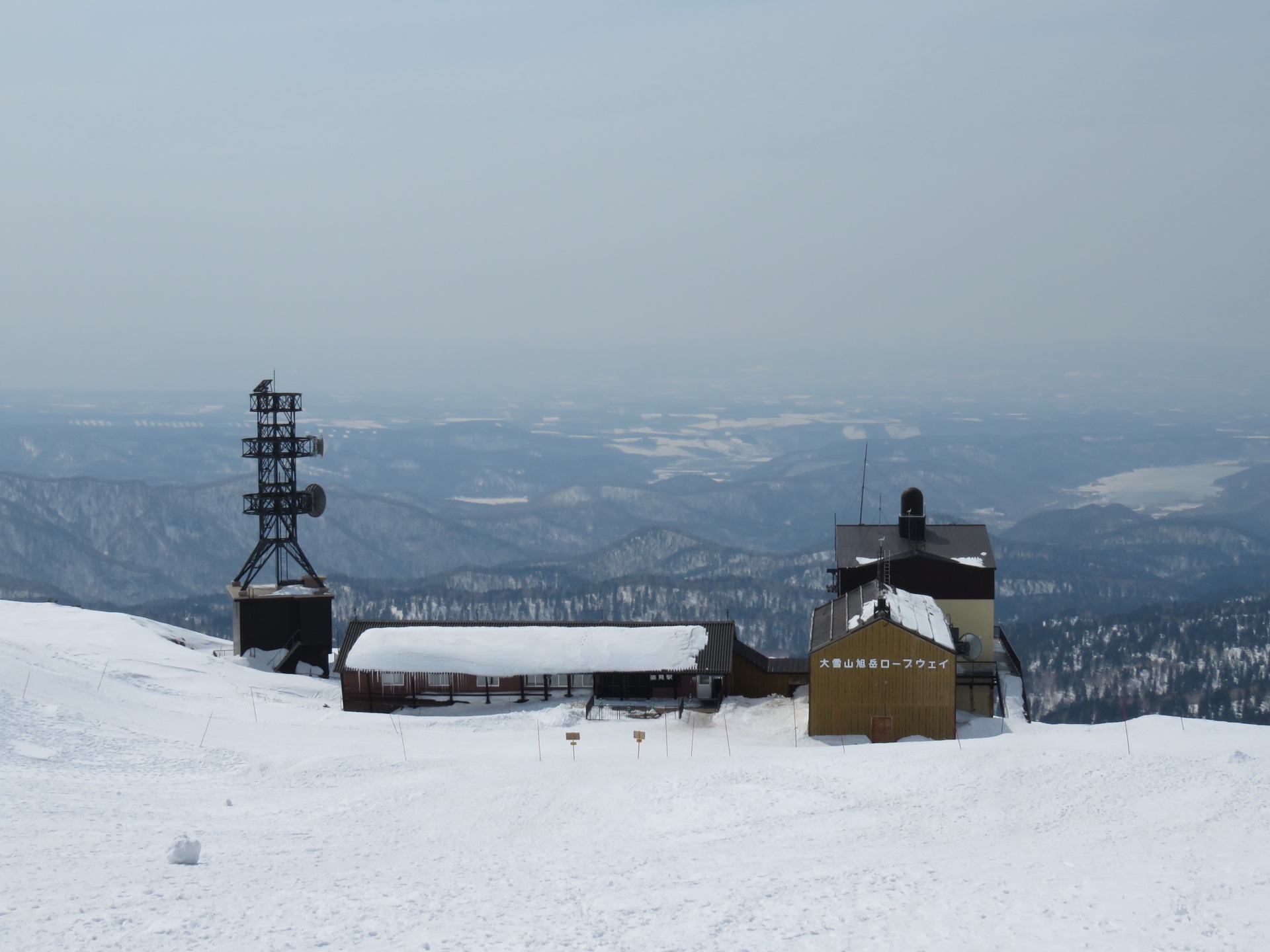 Ropeway towers and the Asahidake upper station fading into cloud above deep snow