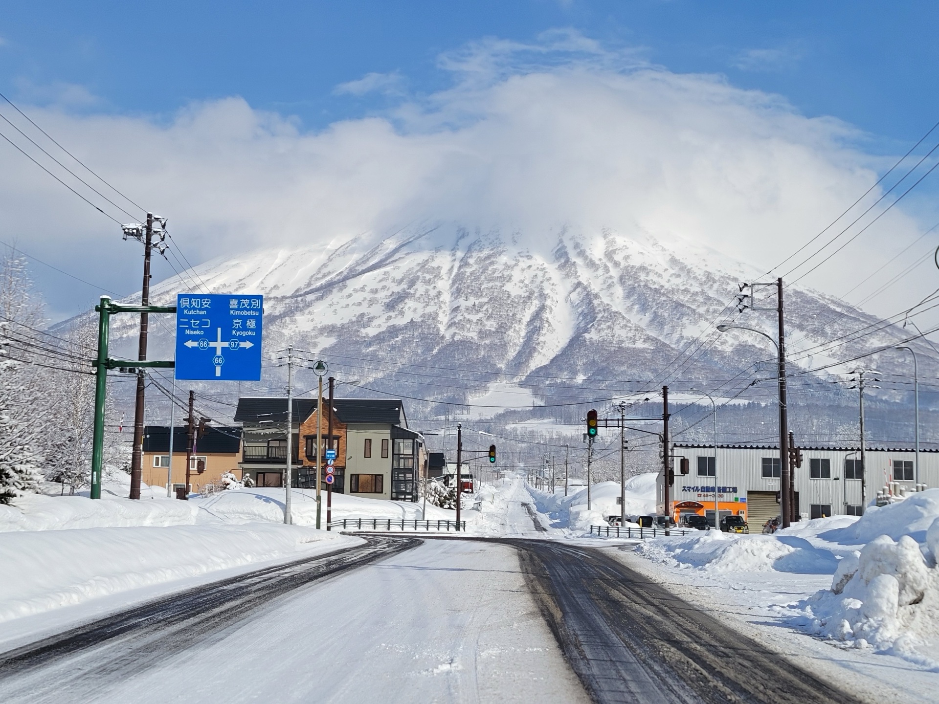 Mount Yōtei rising beyond a snow-covered road and buildings