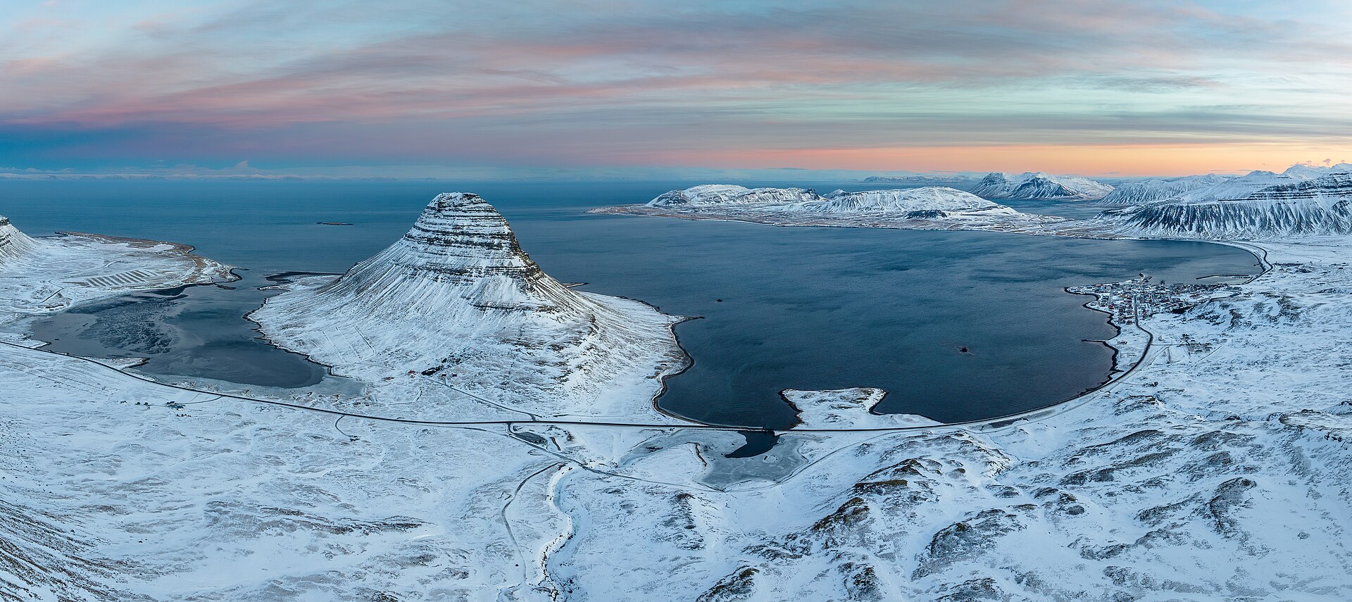 A winter panorama of Kirkjufell, fjord and snowy mountains