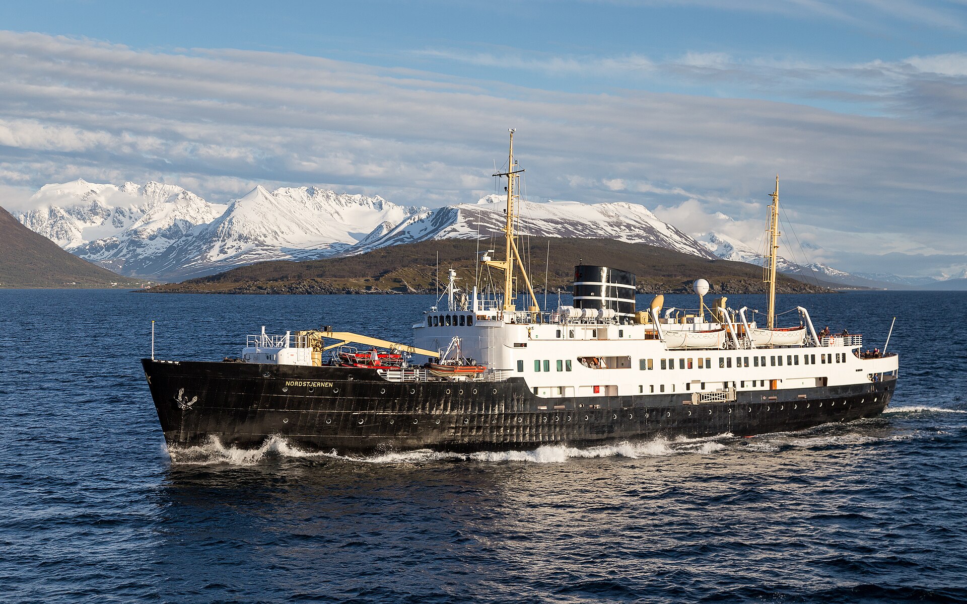 A ship crossing Lyngenfjord beneath steep snow-covered mountains