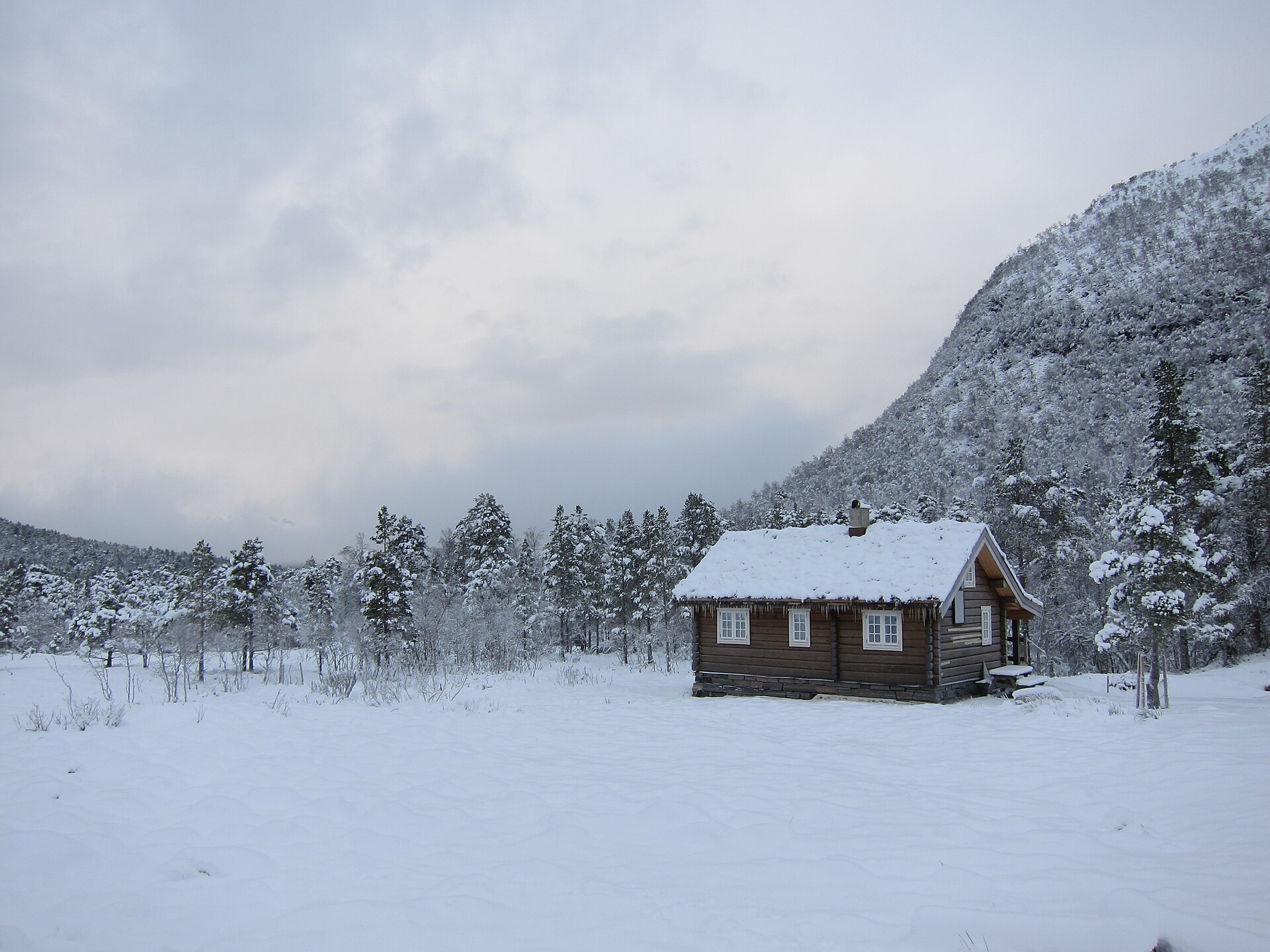 A traditional Norwegian wooden cabin deep in snow at Rekdalsetra