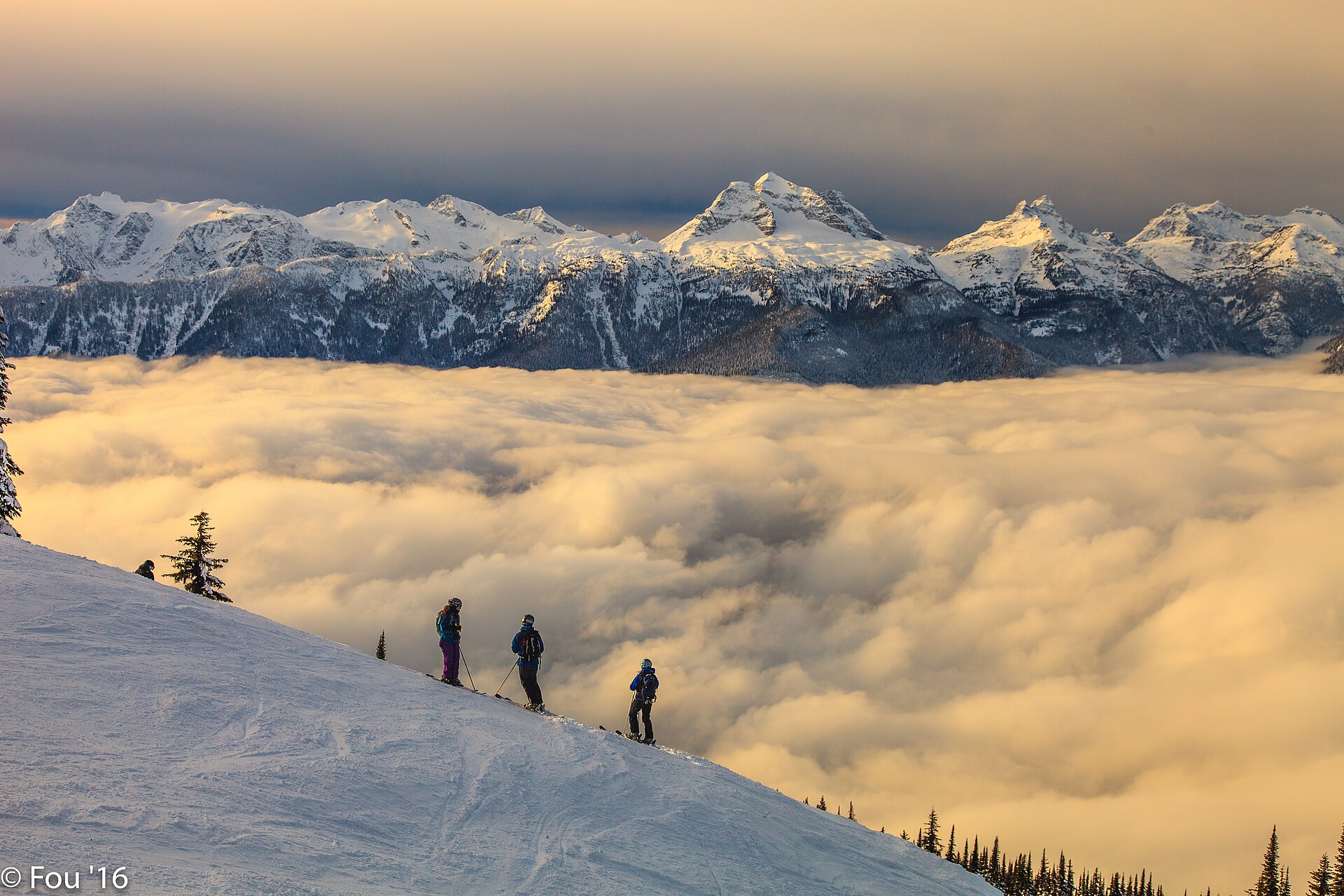 Skiers above a sea of cloud with the Mount Begbie range beyond