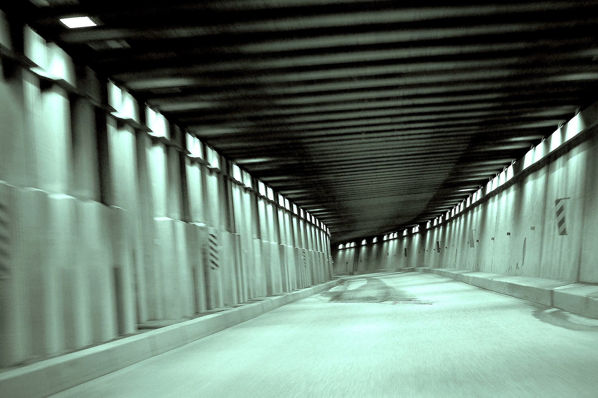 Inside a highway snowshed at Rogers Pass, its lit concrete gallery running away beneath the roof beams