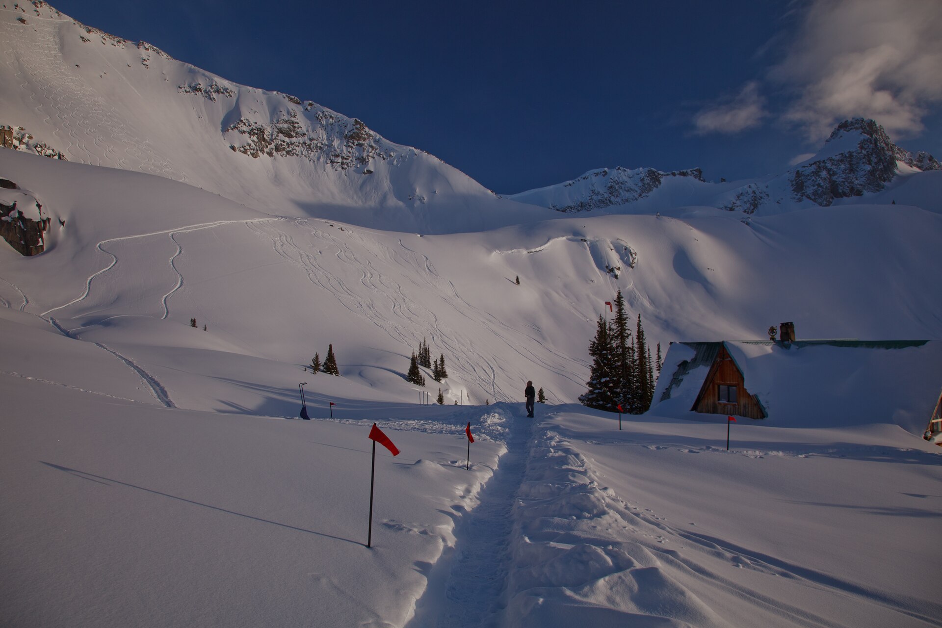 A remote backcountry lodge beneath snowy Selkirk Mountains at dusk