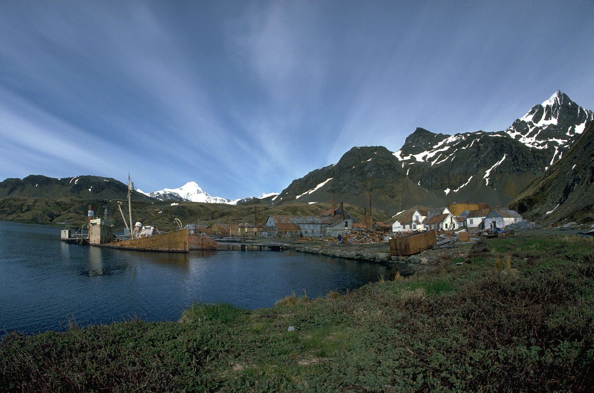 Grytviken's historic waterfront beneath dark ridges and snowy mountains