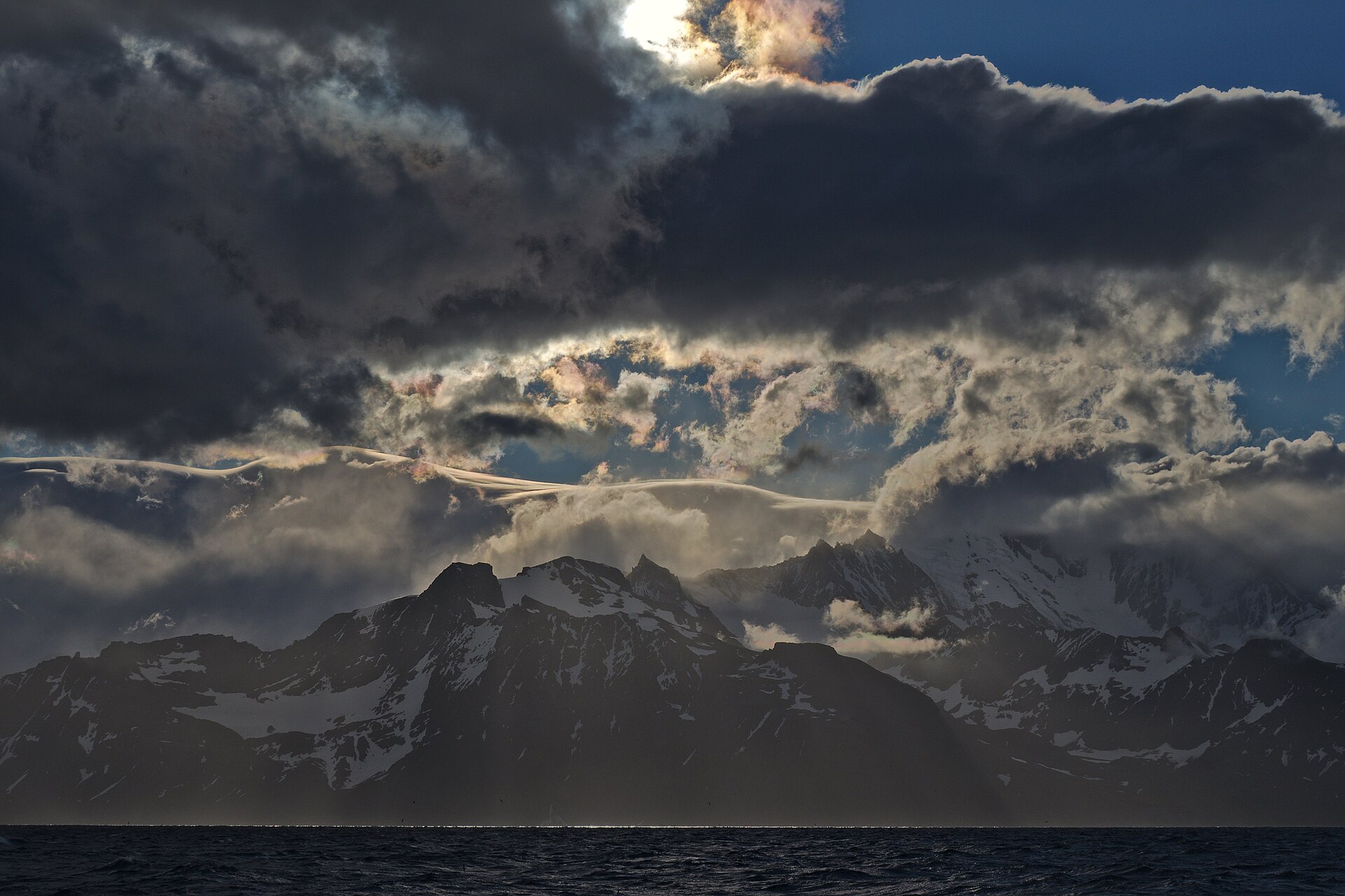 Dark clouds opening above the snow-covered mountains of South Georgia