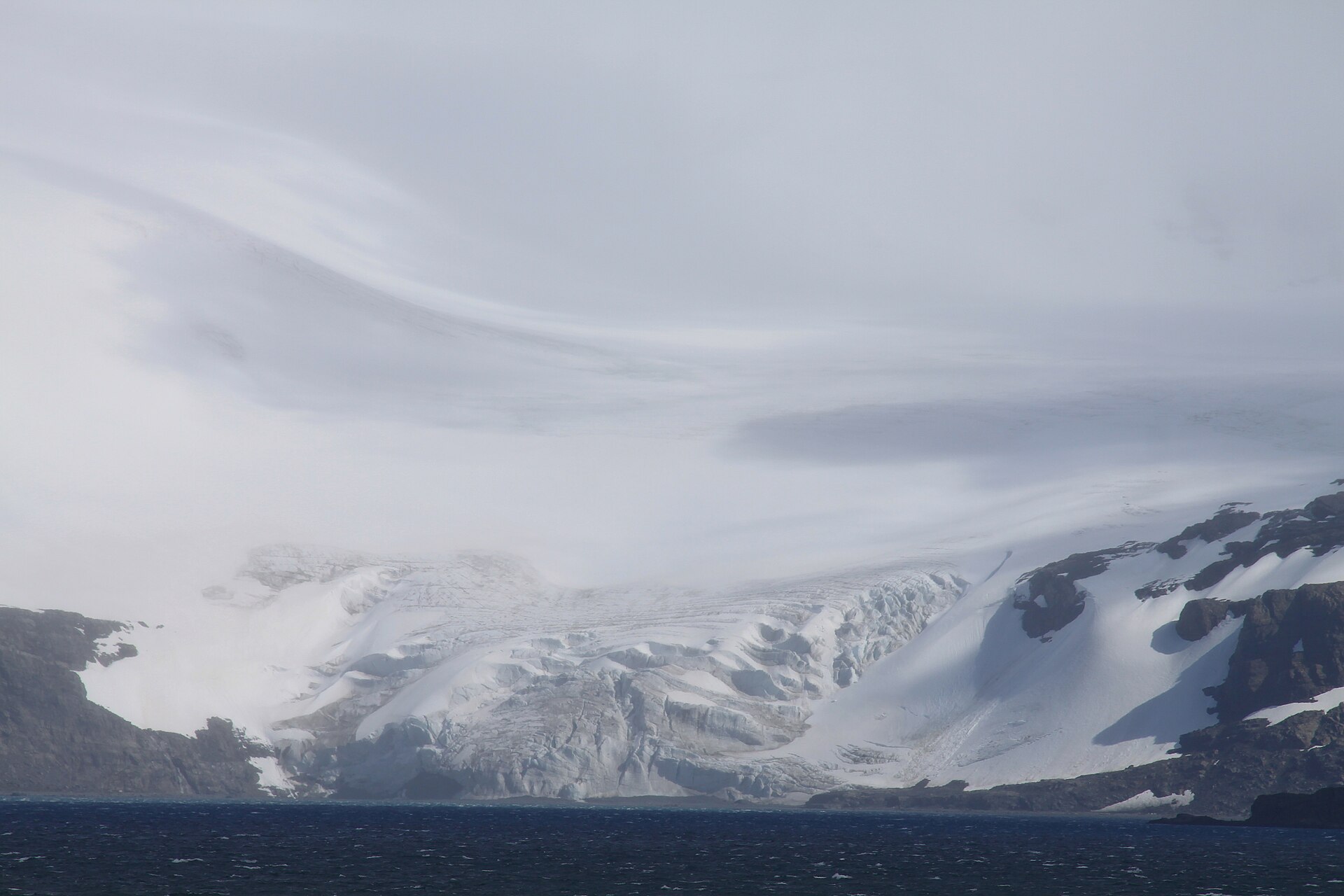 A snowy valley leading inland from Possession Bay beneath broken cloud