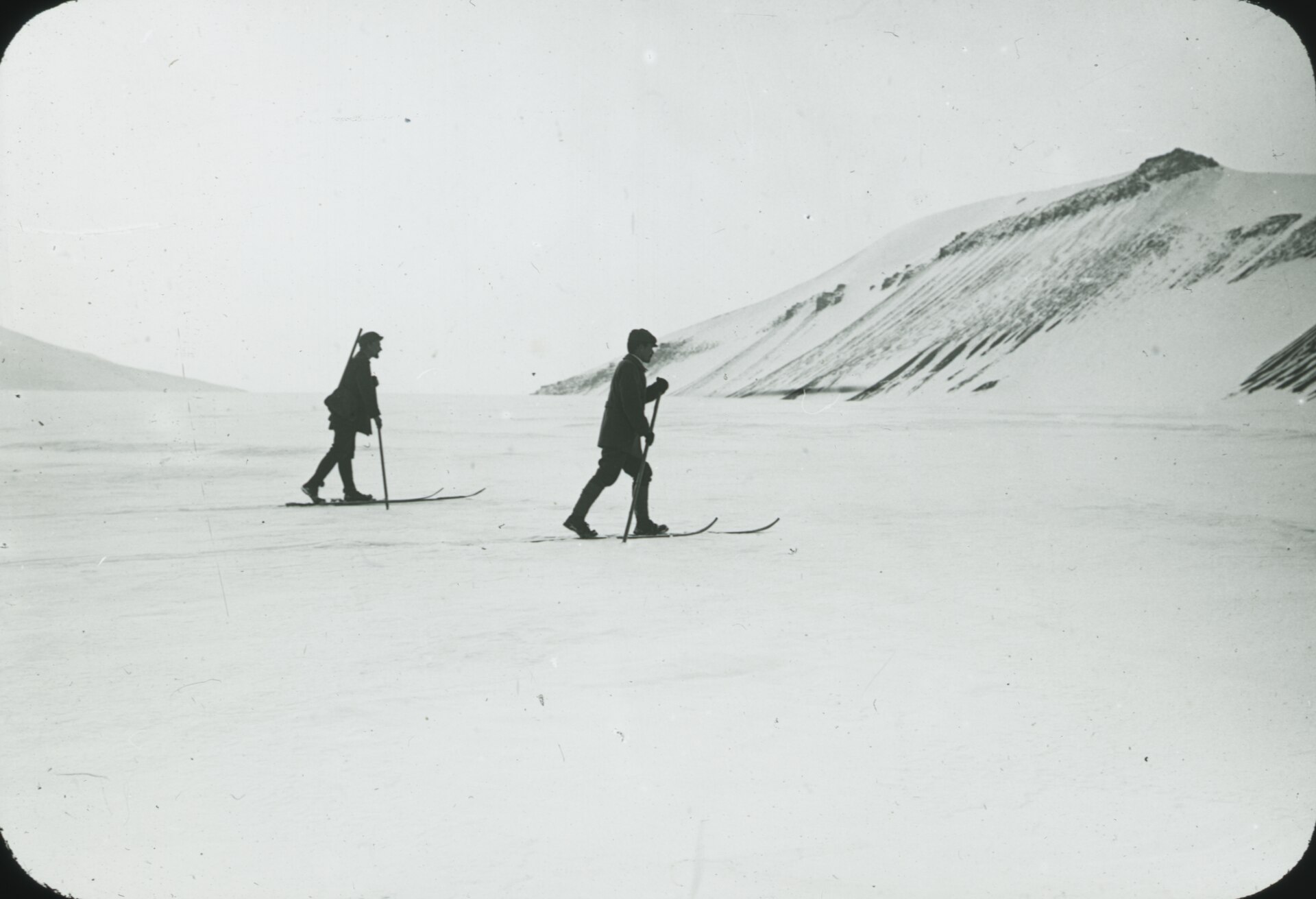 Two early expedition skiers crossing an open snowfield in Spitsbergen