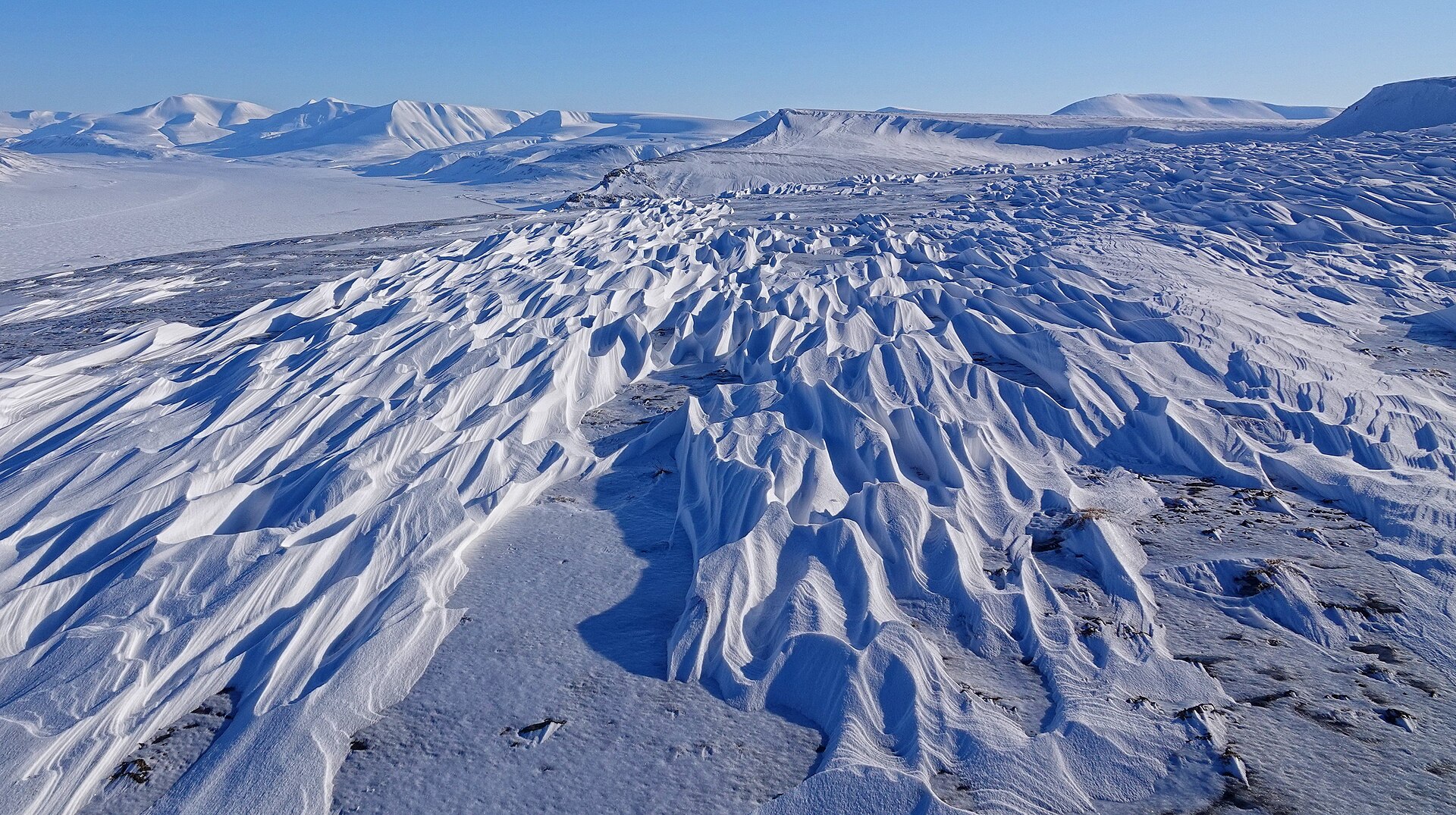 Wind-sculpted sastrugi on a snowy ridge above Adventdalen in Svalbard