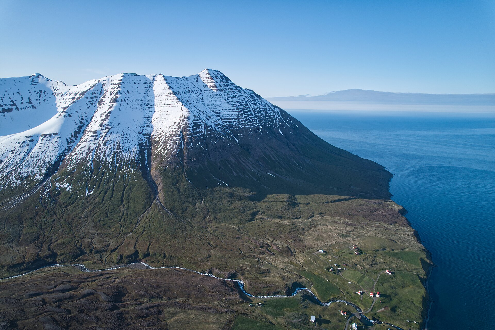 Aerial view of snow-striped Arnfinnsfjall meeting the sea