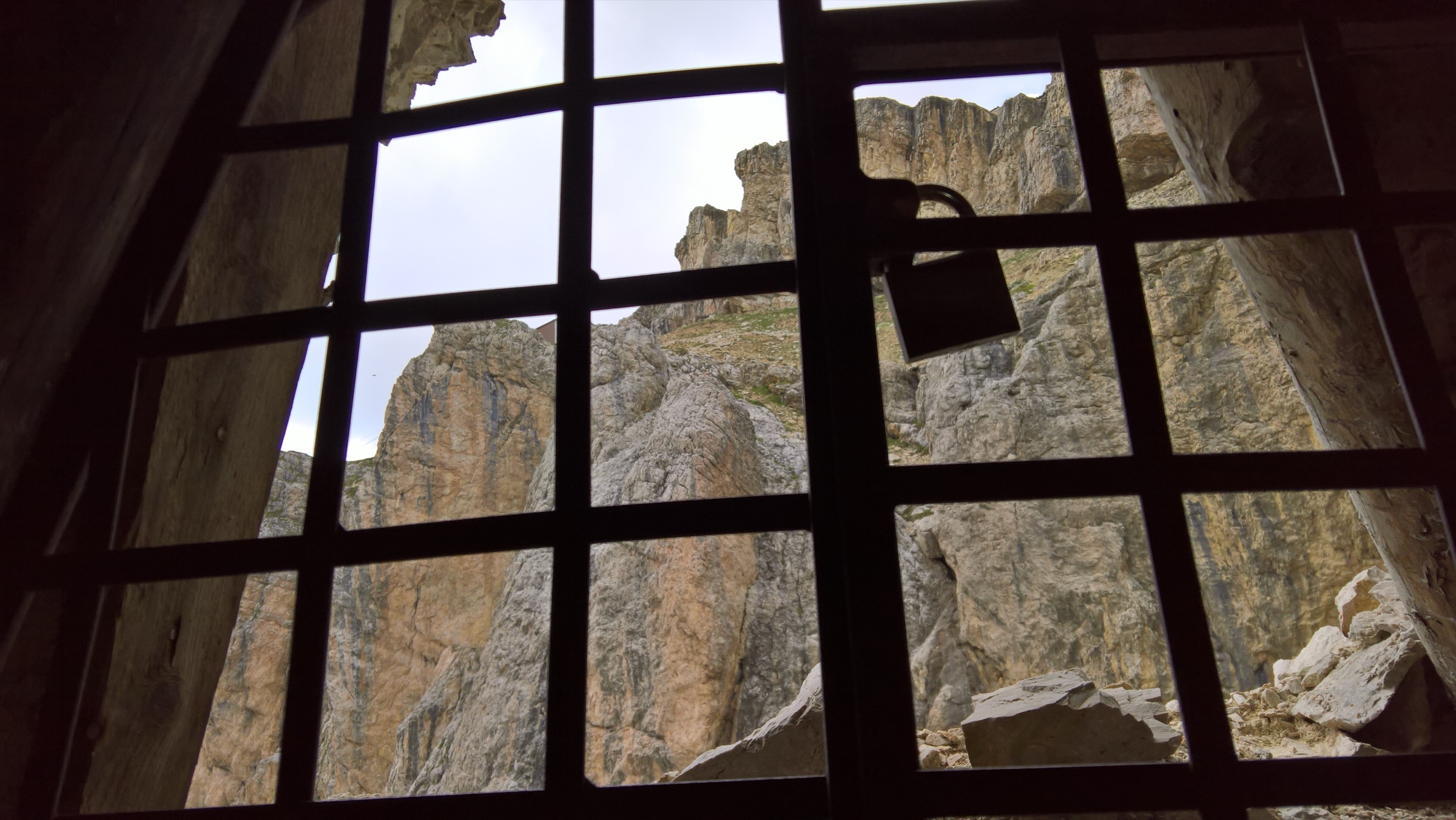 View out through the wooden-grid window of a restored WWI Italian military gallery on Mount Lagazuoi, Dolomites