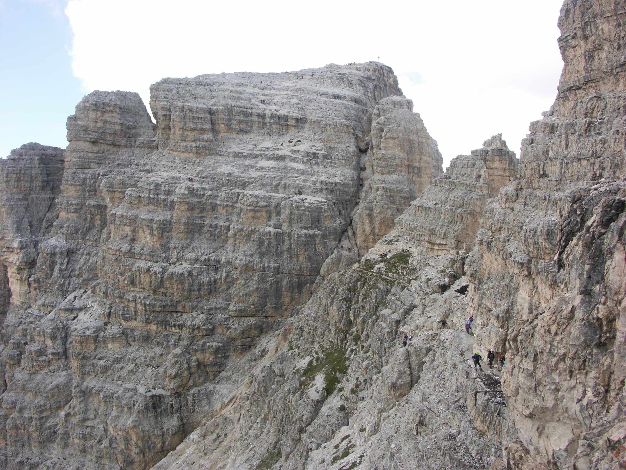 Tiny silhouettes of climbers on the cabled ledge below the north face of the Paternkofel (Monte Paterno) on the Innerkofler–De Luca via ferrata, Sexten Dolomites