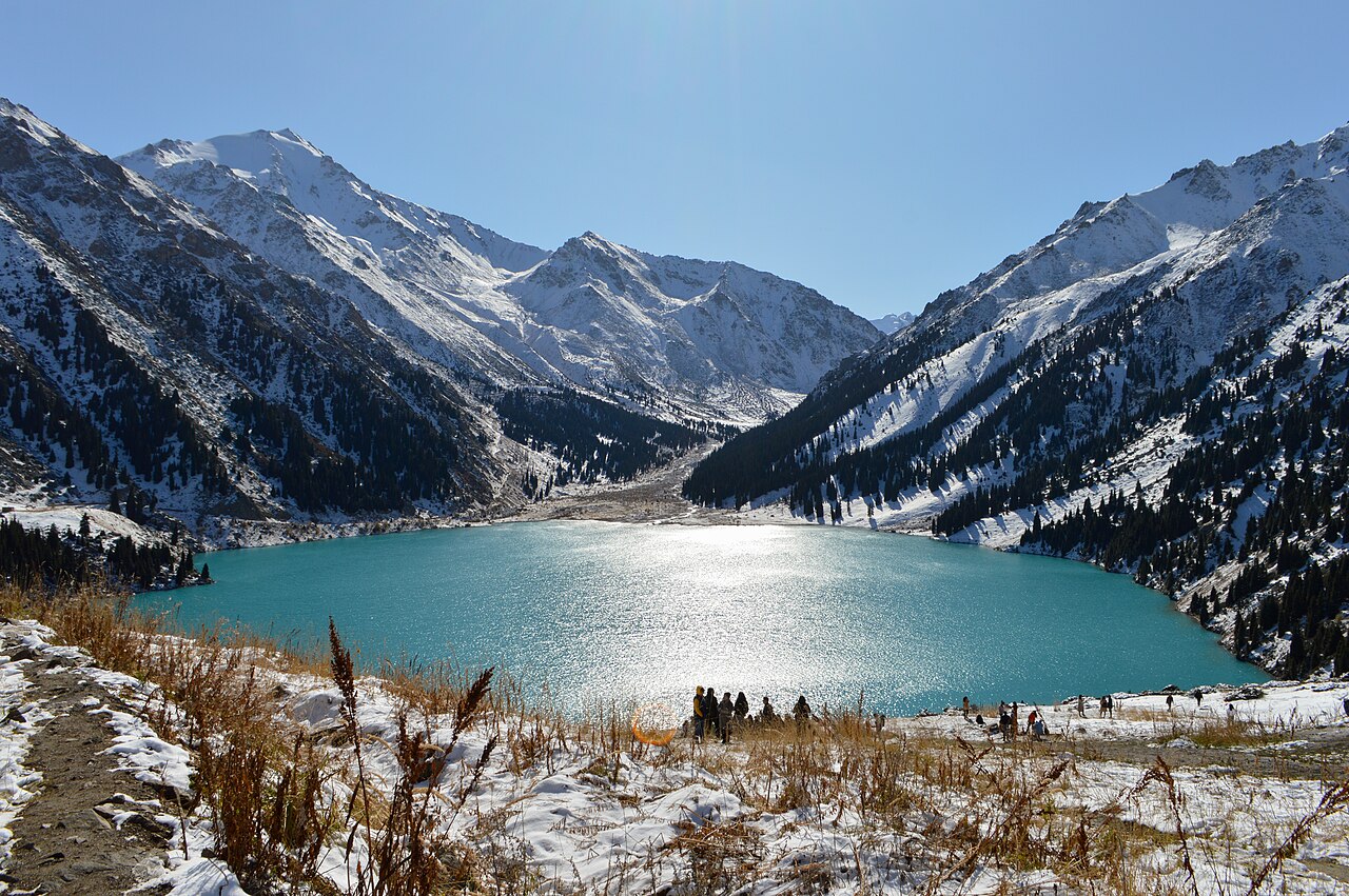 Big Almaty Lake beneath steep snow-streaked mountains