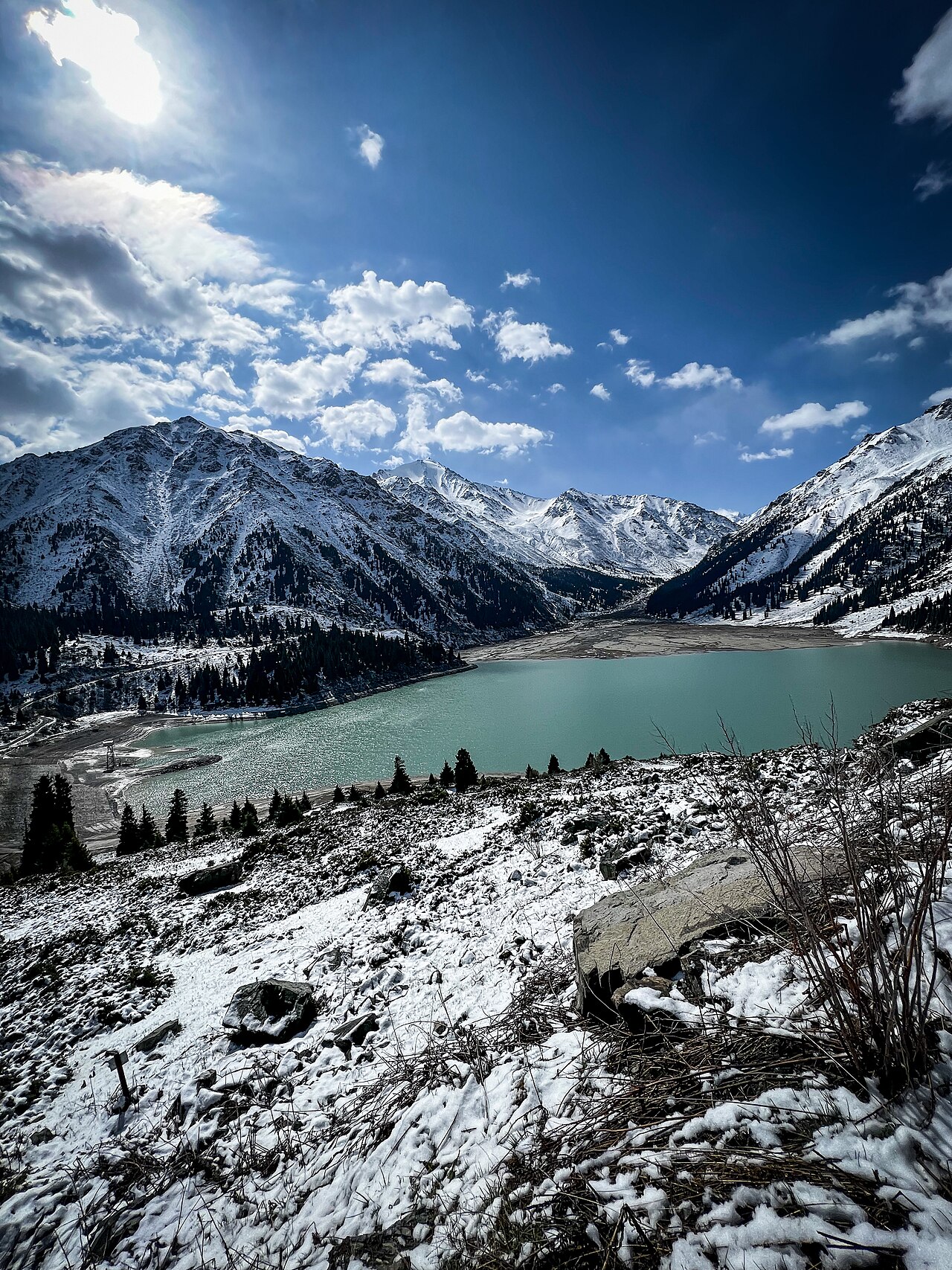 Snowy cirques reflected in Big Almaty Lake under broken cloud