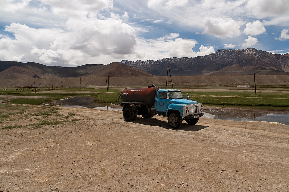 A blue truck on the edge of Murghab beneath high barren mountains