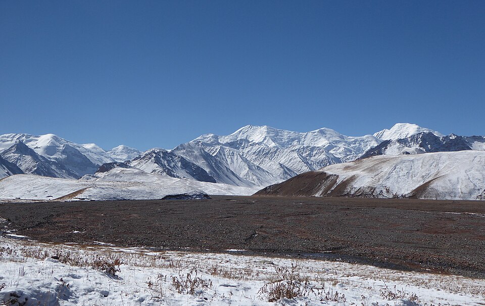 A broad snow-covered Pamir plateau beneath a chain of white mountains