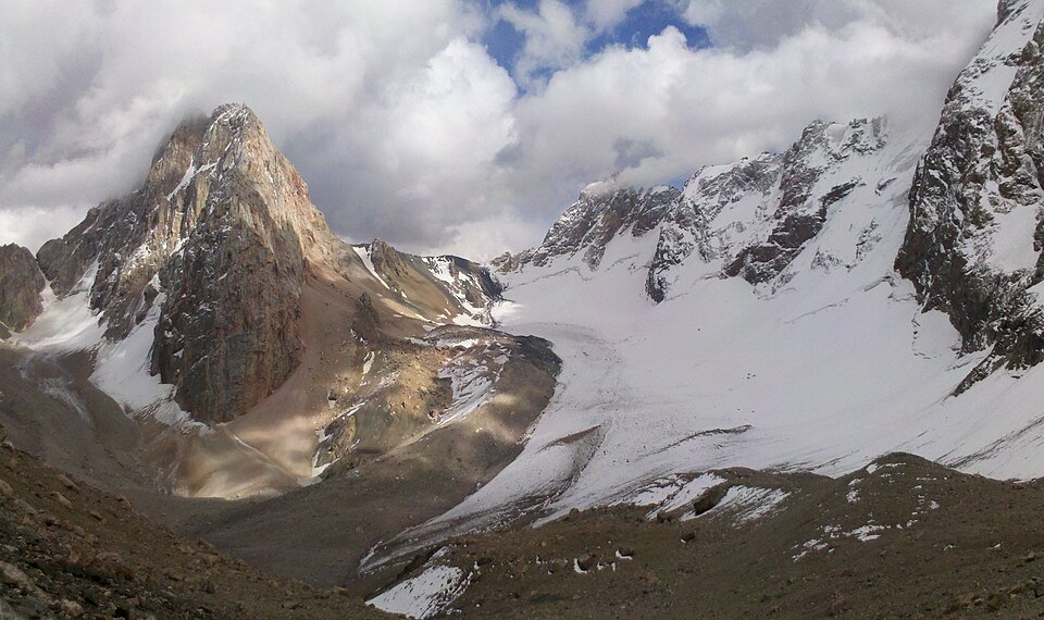 Snow and glacier beneath sharp walls at Dvoynoy Pass in the Fann Mountains