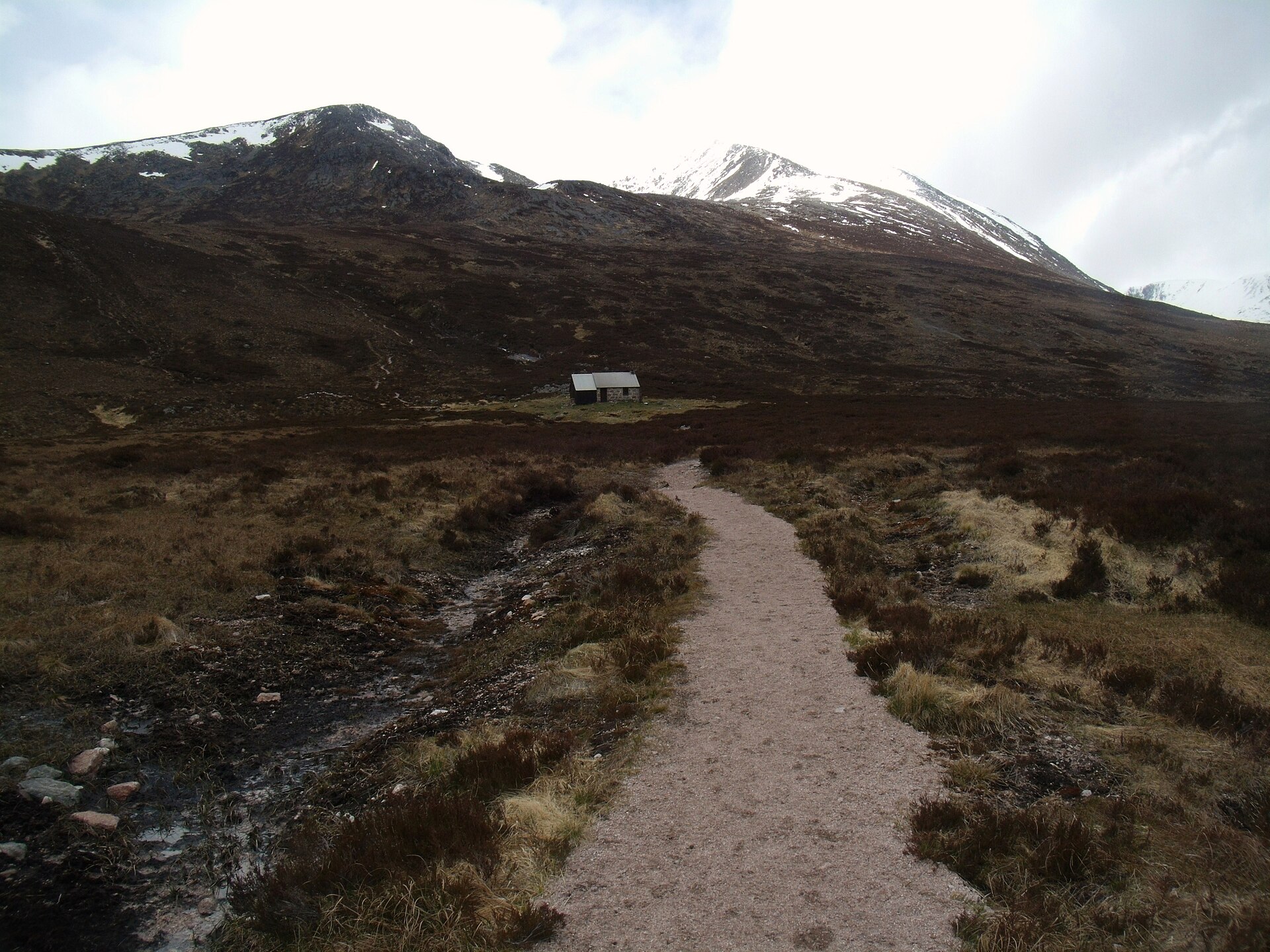 Walkers approaching Corrour bothy beneath the mountains of the Lairig Ghru