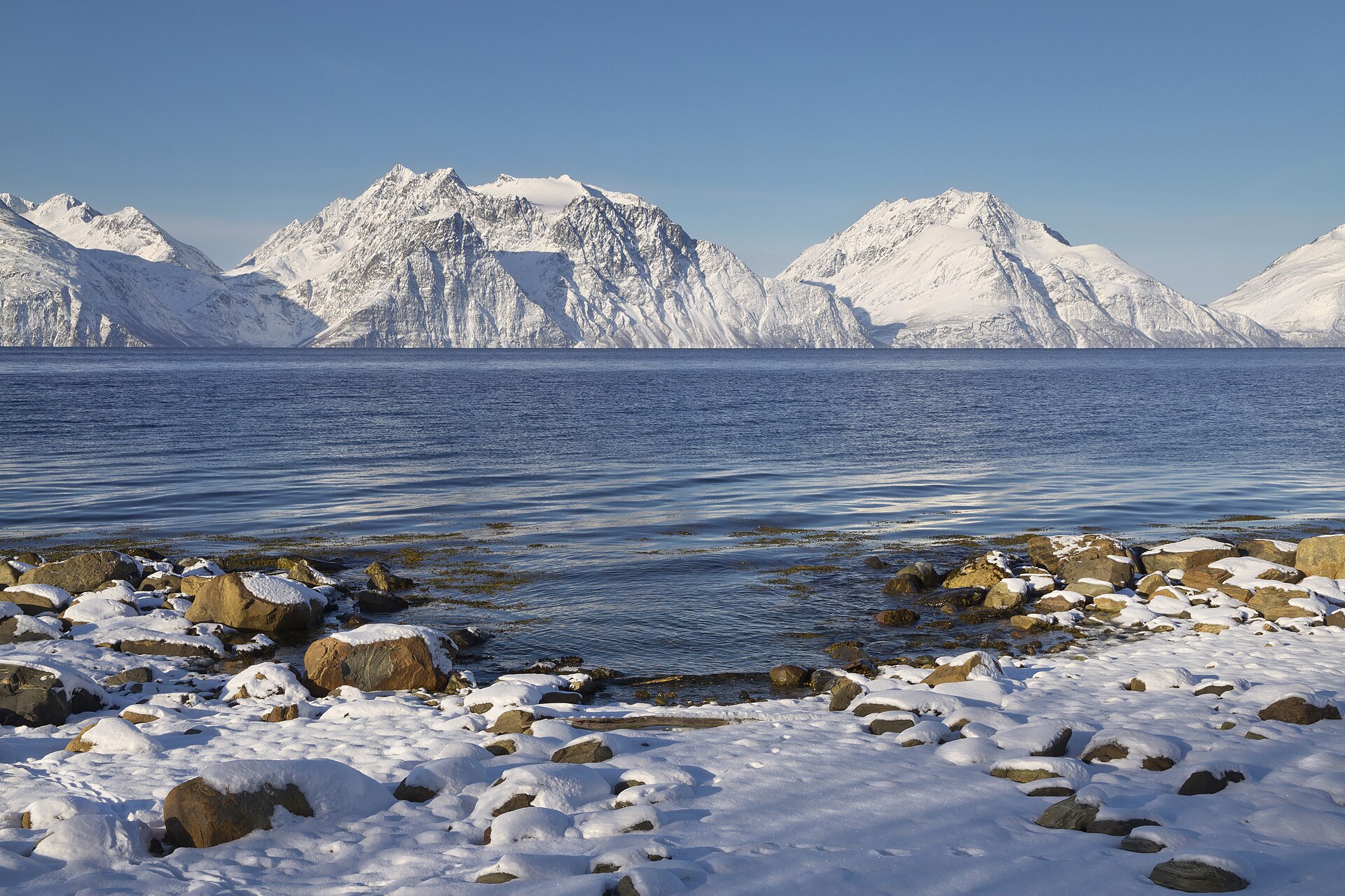 Støvelfjellet and Vaggastindan rising beyond a snowy Lyngen shoreline