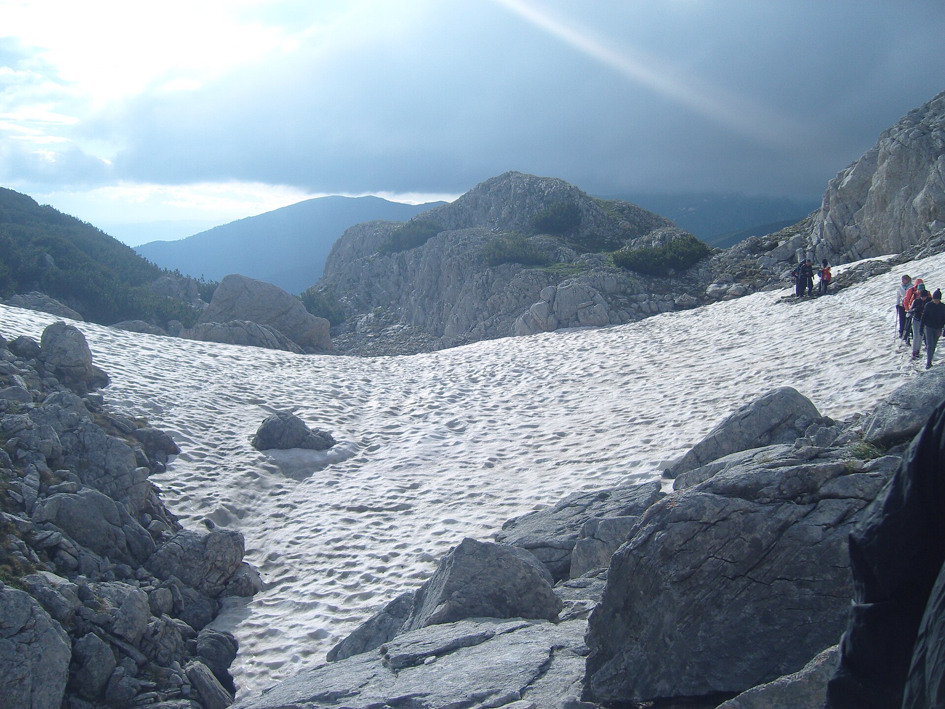 Mountaineers crossing a lingering snowfield in the Pirin Mountains