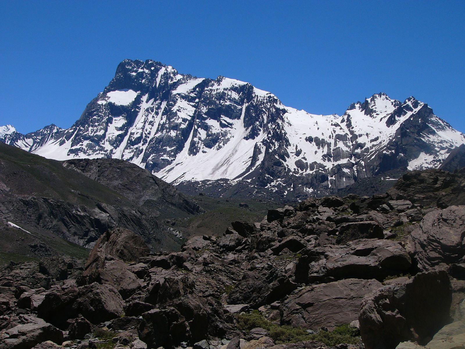 Cerro Arenas rising above a rocky high-Andes approach with snow on its faces