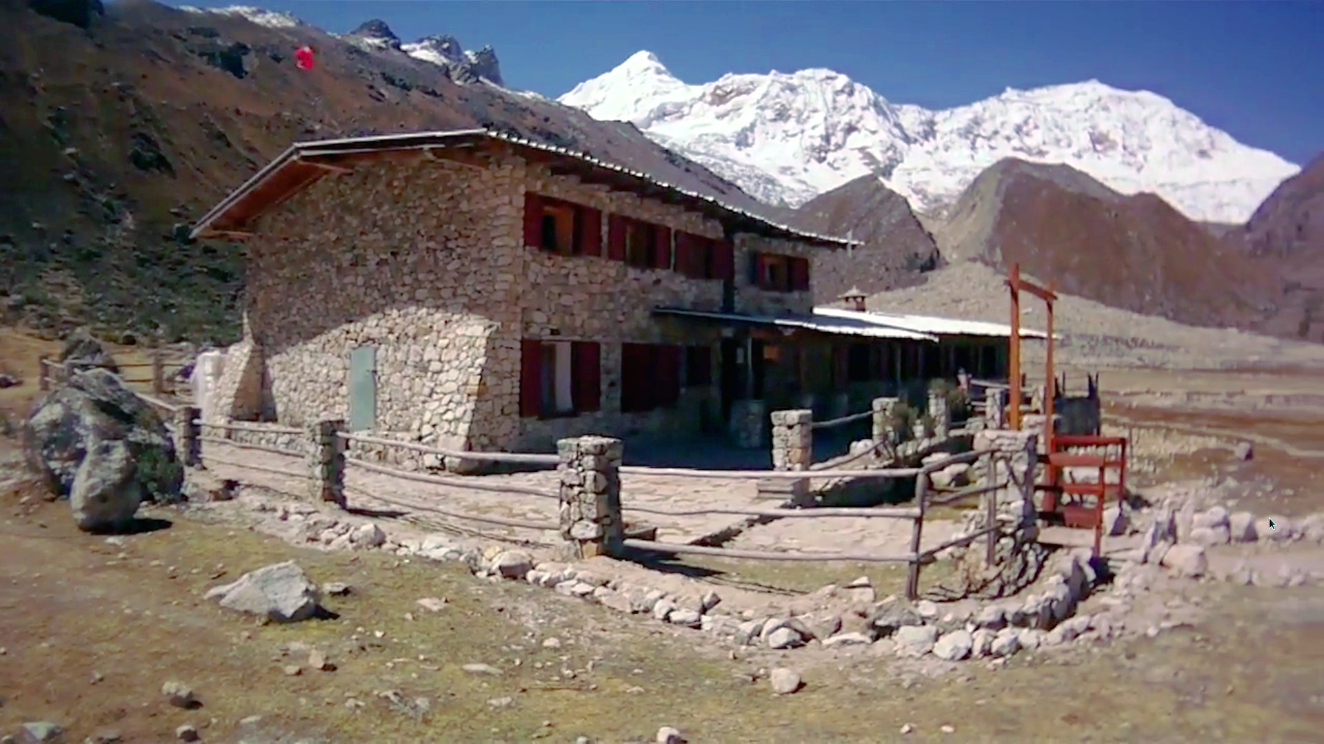 The stone Refugio Ishinca with high snow peaks behind