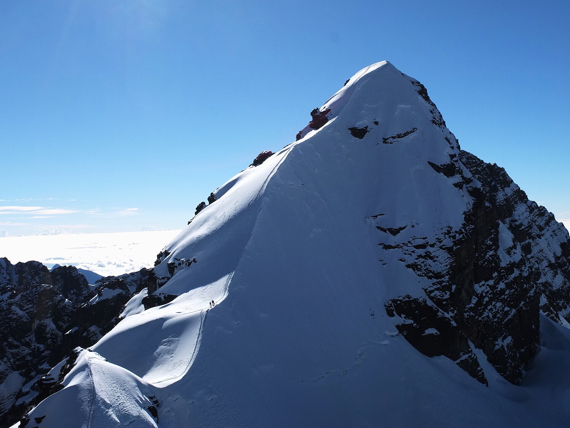 Climbers ascending the narrow snow ridge of Pequeño Alpamayo